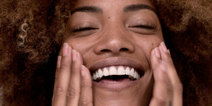 Image of woman smiling and touching her face